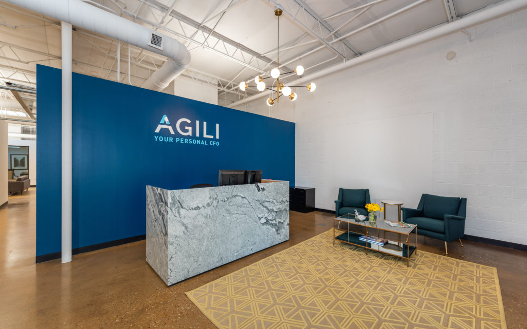 Agili office front desk with blue background wall with Agili logo letters on wall.
