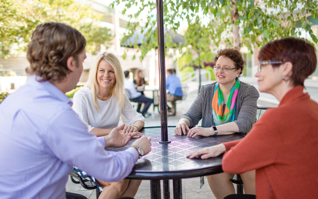 Agili team members Cynthia Levine, Conor Clark, Elissa Wurf, and Stacey Standlick sit at an outdoor table talking
