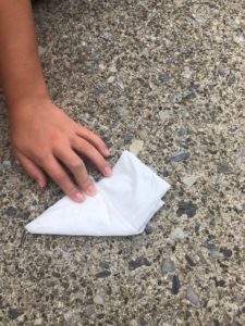 Girl finishing folding plastic grocery bag into triangles for litter collection