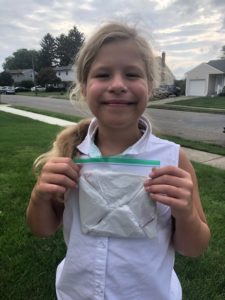 Girl placing plastic grocery bag "football" in sandwich bag for litter collection