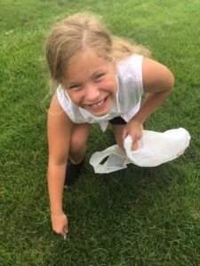 Girl picking up litter with stored plastic grocery bag