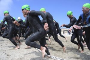 Triathletes running into the water for their swim